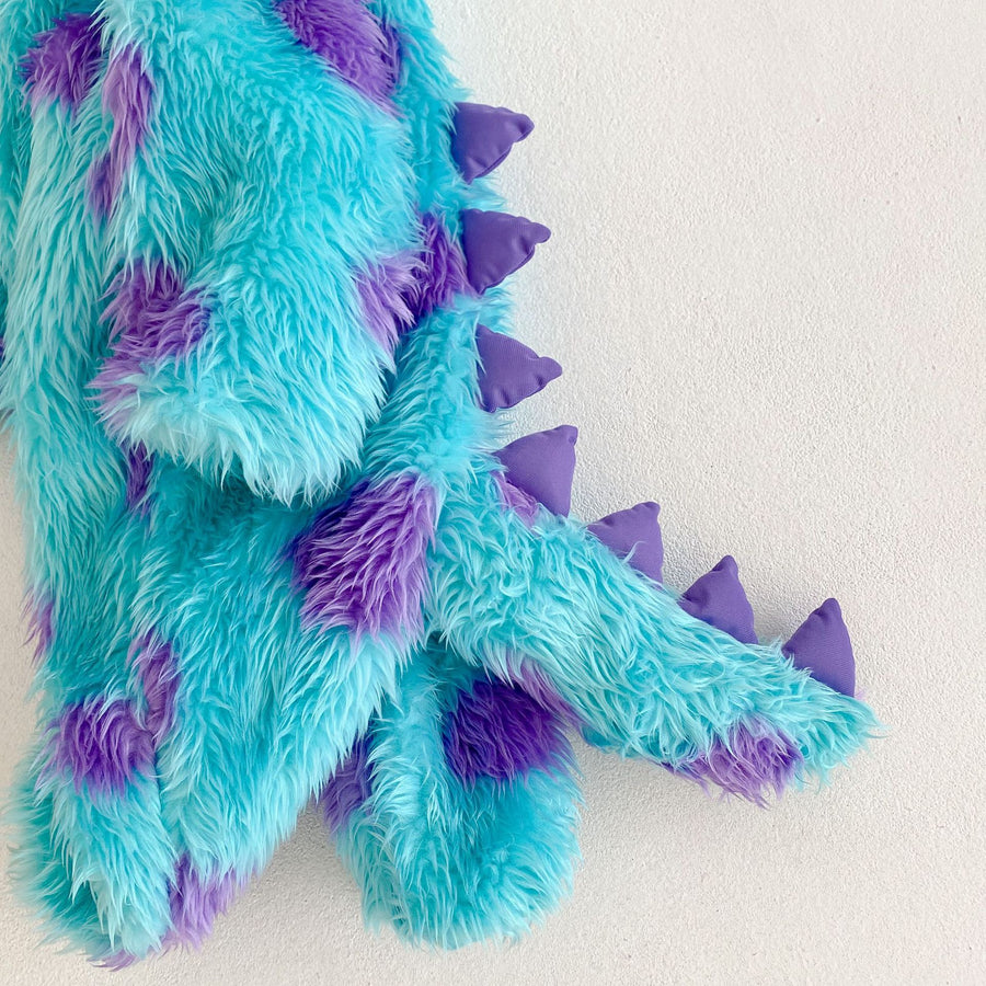 Close-up of the padded purple spikes set into the shaggy turquoise pile along the back and tail